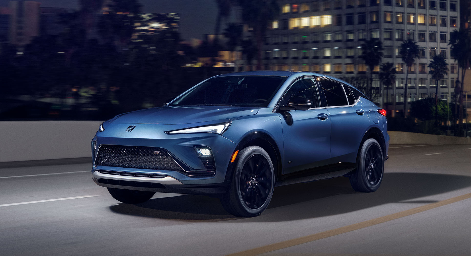 Une Buick Envista bleue et élégante dans une scène urbaine nocturne