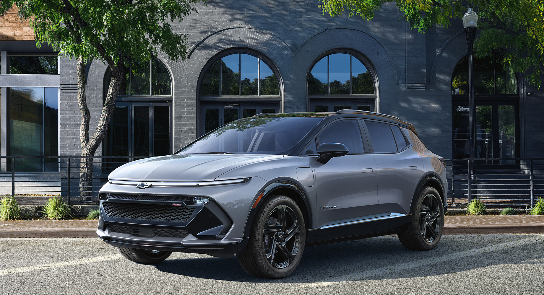 Silver Chevrolet Equinox EV is parked on the side of the road in front of a building