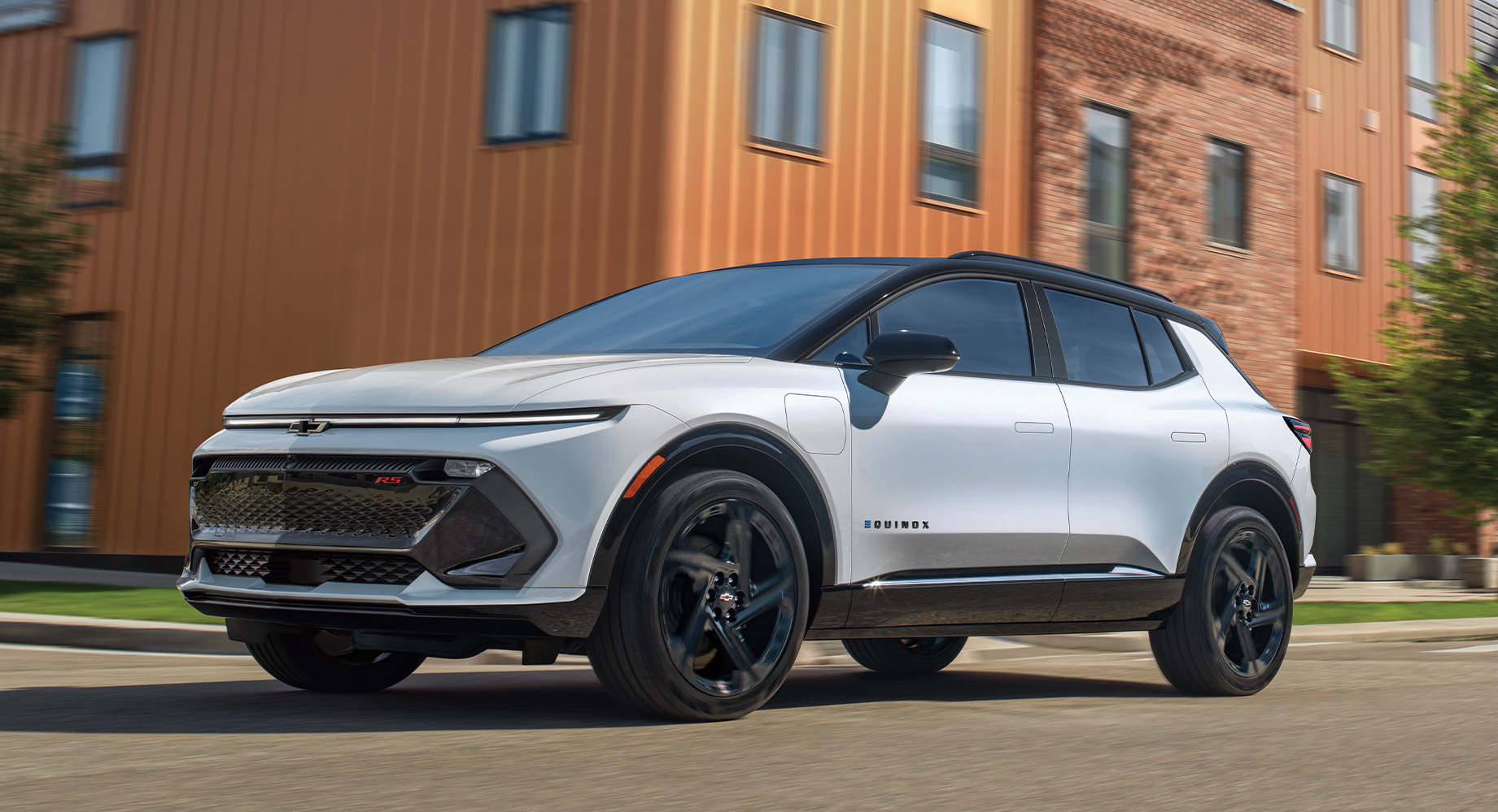 White Chevrolet Equinox EV parked in front of a large orange building