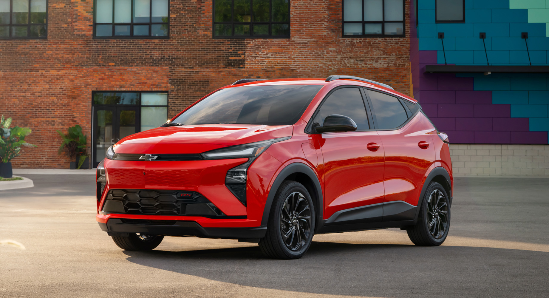 un Chevy Equinox EV blanc roulant devant un bâtiment en briques