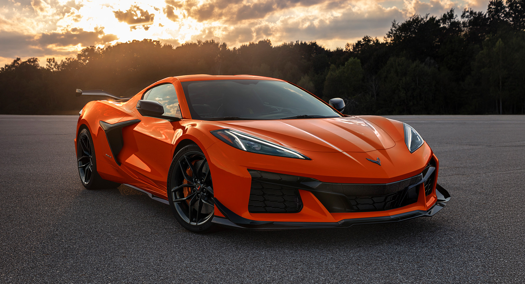 Chevrolet Corvette d'un orange éclatant sur un parking en asphalte, à l'heure dorée