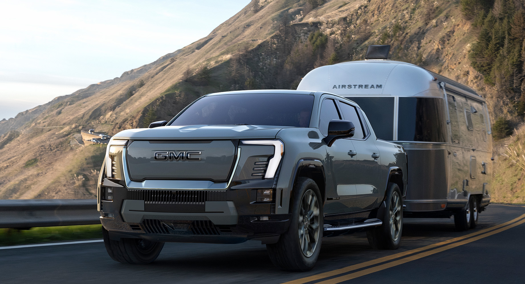 GMC Sierra EV is towing a trailer down a road