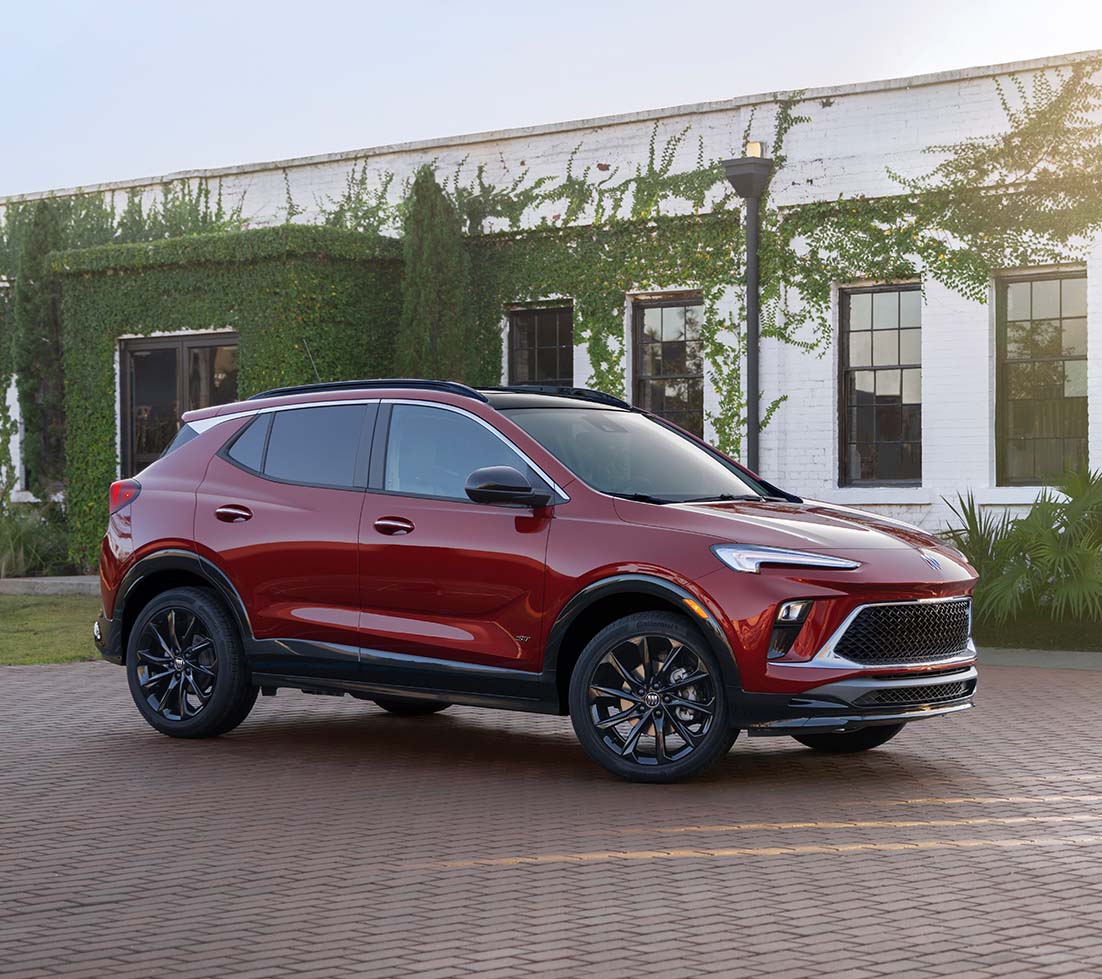 Red Buick Encore is parked in front of a white building