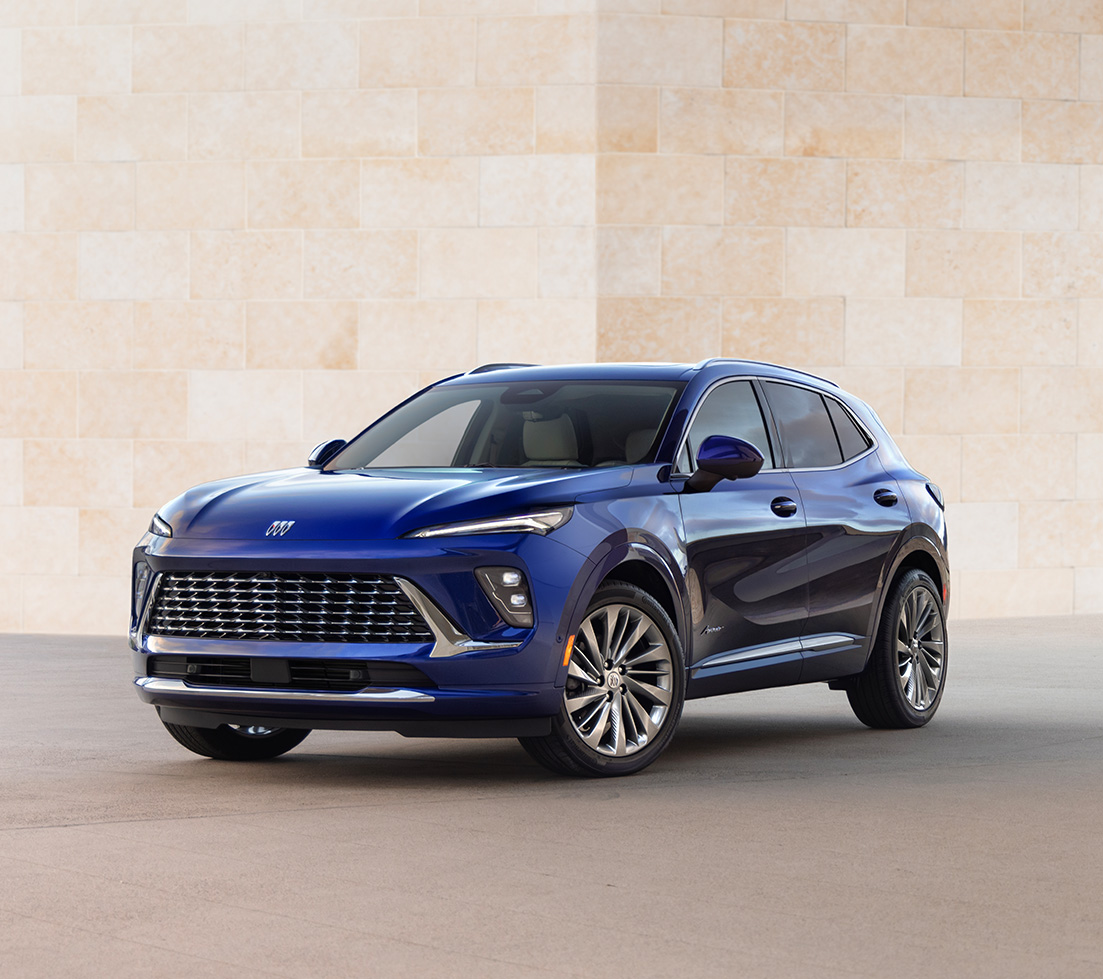 Blue Buick Envision is parked in front of a beige stone wall