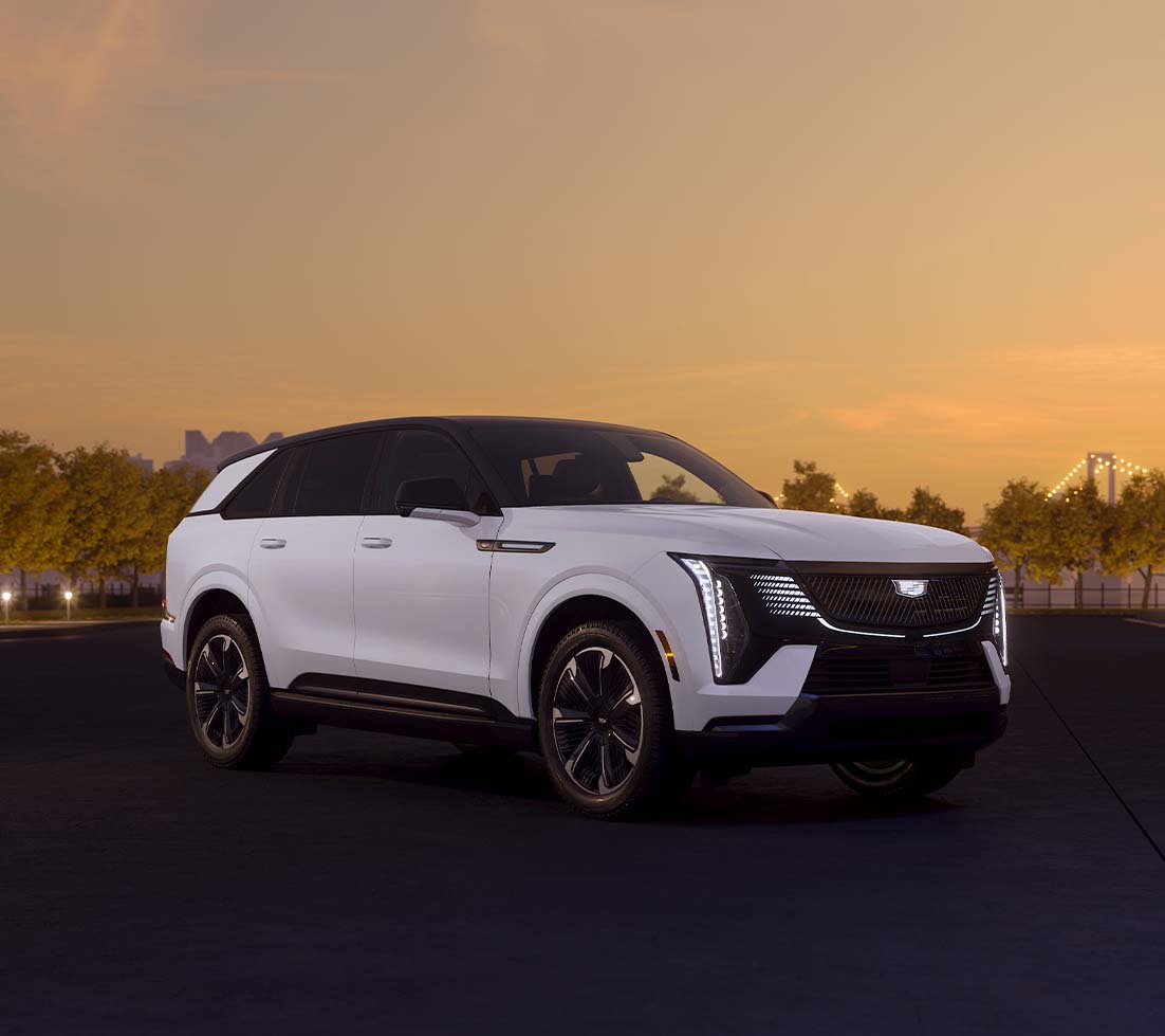 White Cadillac Escalade IQ parked in front of a sunset