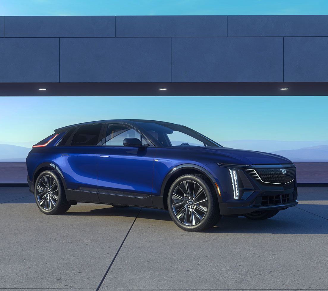 Blue Cadillac LYRIQ is parked in front of a building
