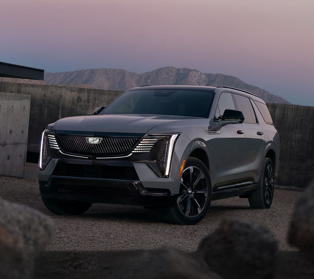 Grey Cadillac Escalade IQL is parked in front of a building in the desert