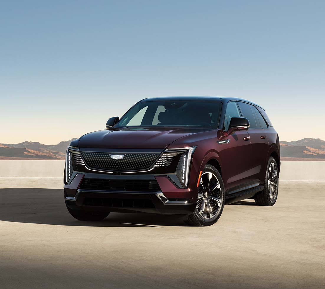 Maroon Cadillac Escalade IQ is parked in the middle of a desert