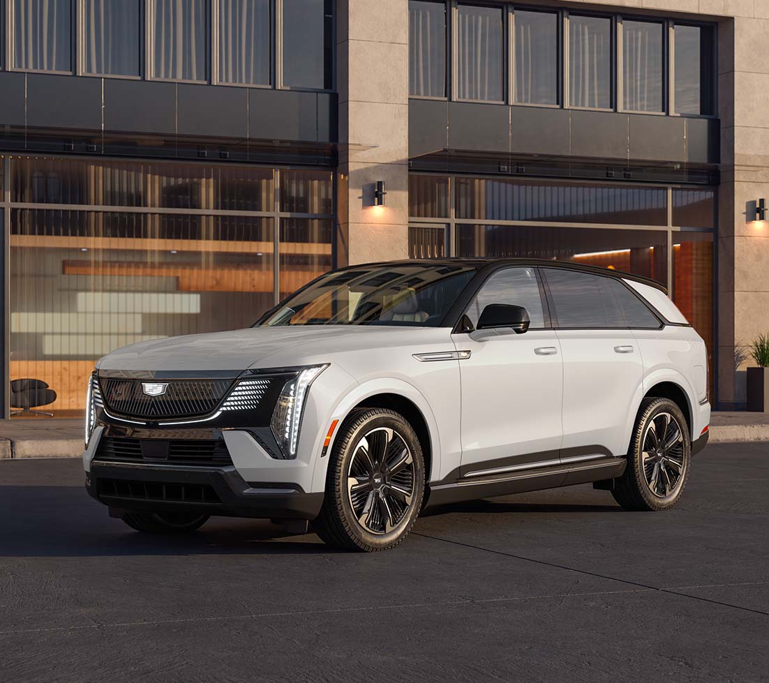 hite Cadillac ESCALADE IQ parked in front of a building