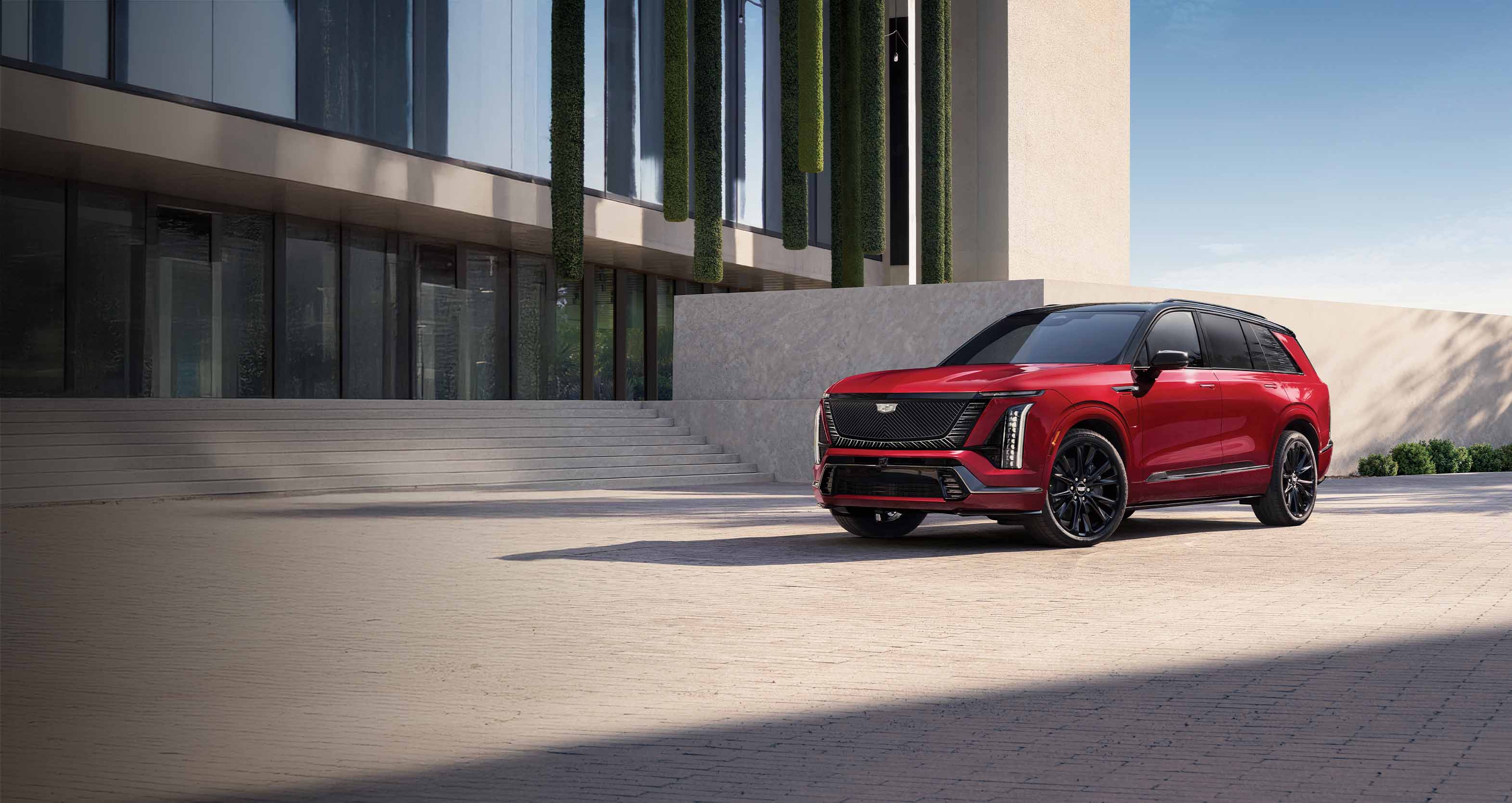 Red Cadillac OPTIQ is parked in front of a building at night