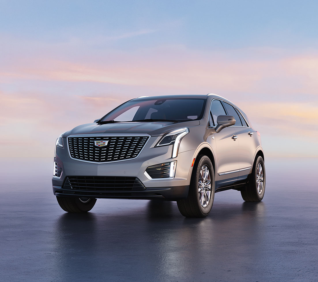 Blue Cadillac XT5 is parked in front of a building