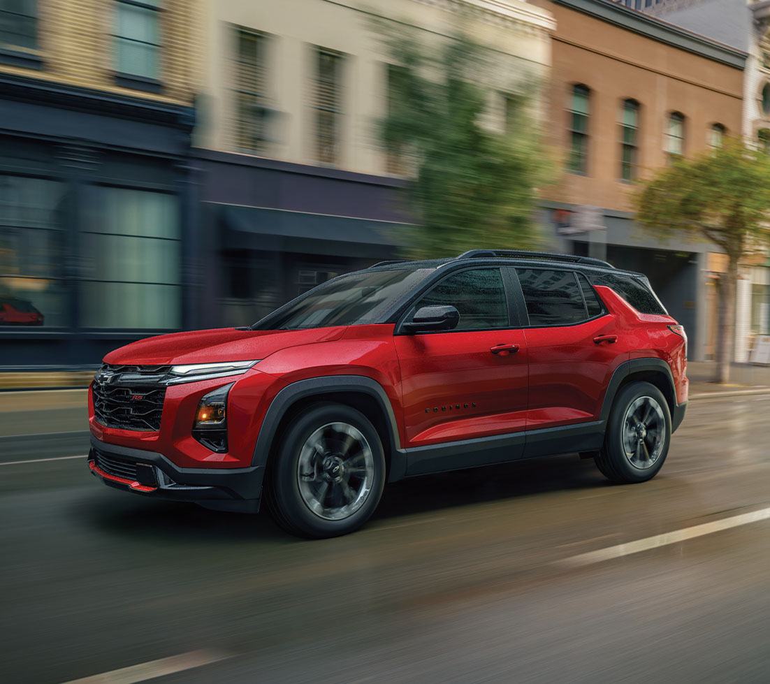 Red Chevrolet Equinox is driving down a city street