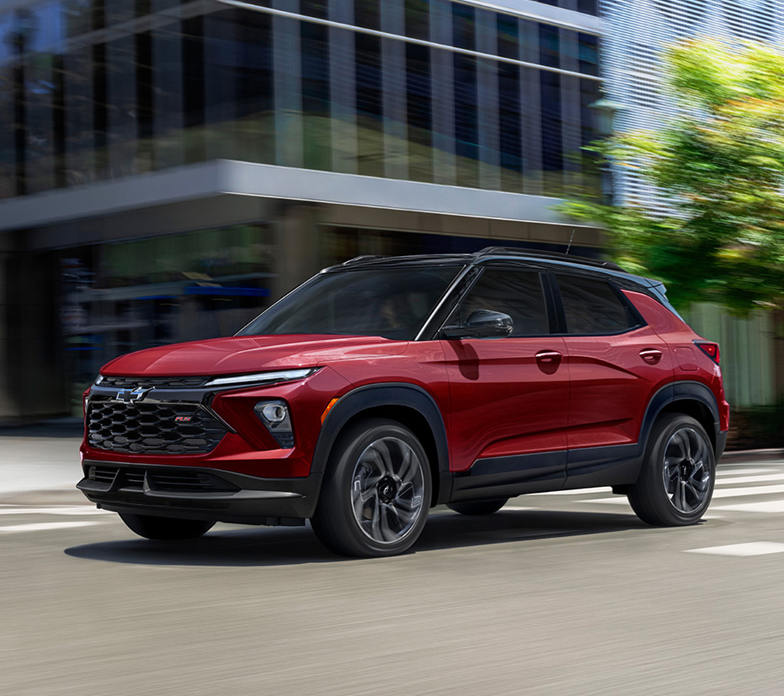 Red Chevrolet Trailblazer is driving down a city street