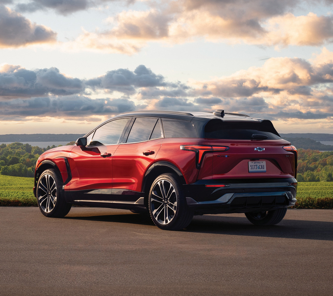 Chevrolet Blazer EV rouge roulant devant un bâtiment vert