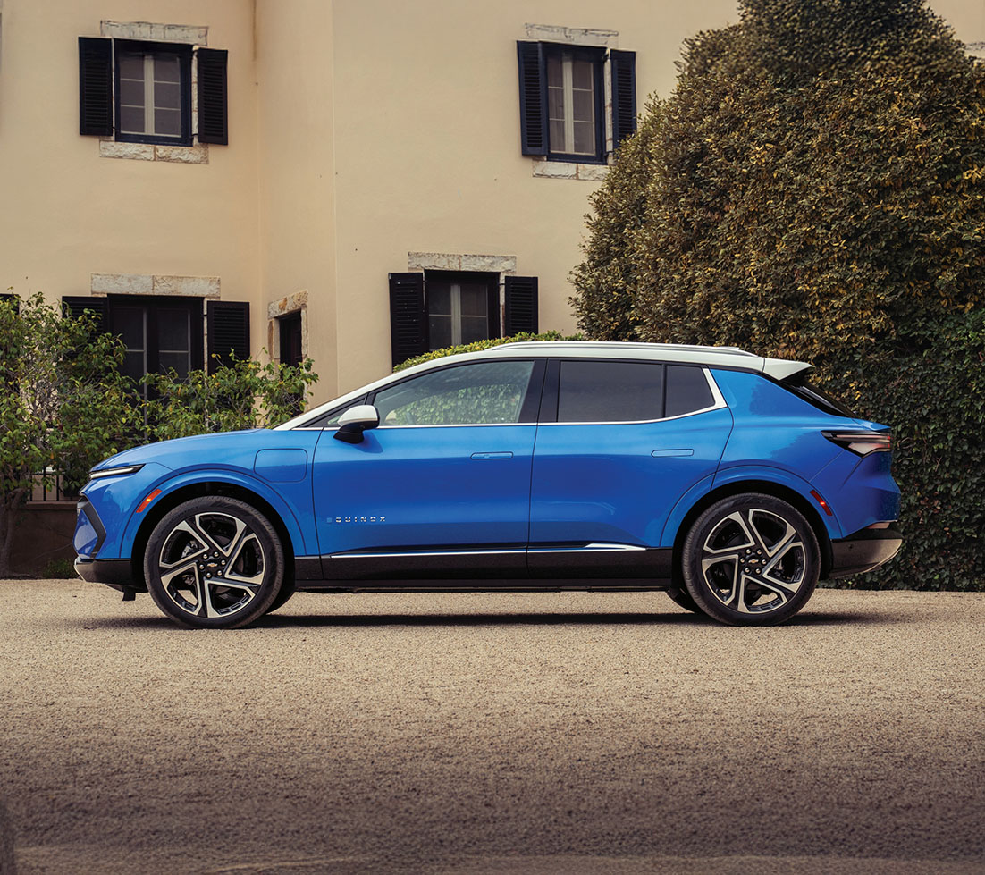 Un Chevy Equinox électrique blanc roulant devant un bâtiment en briques