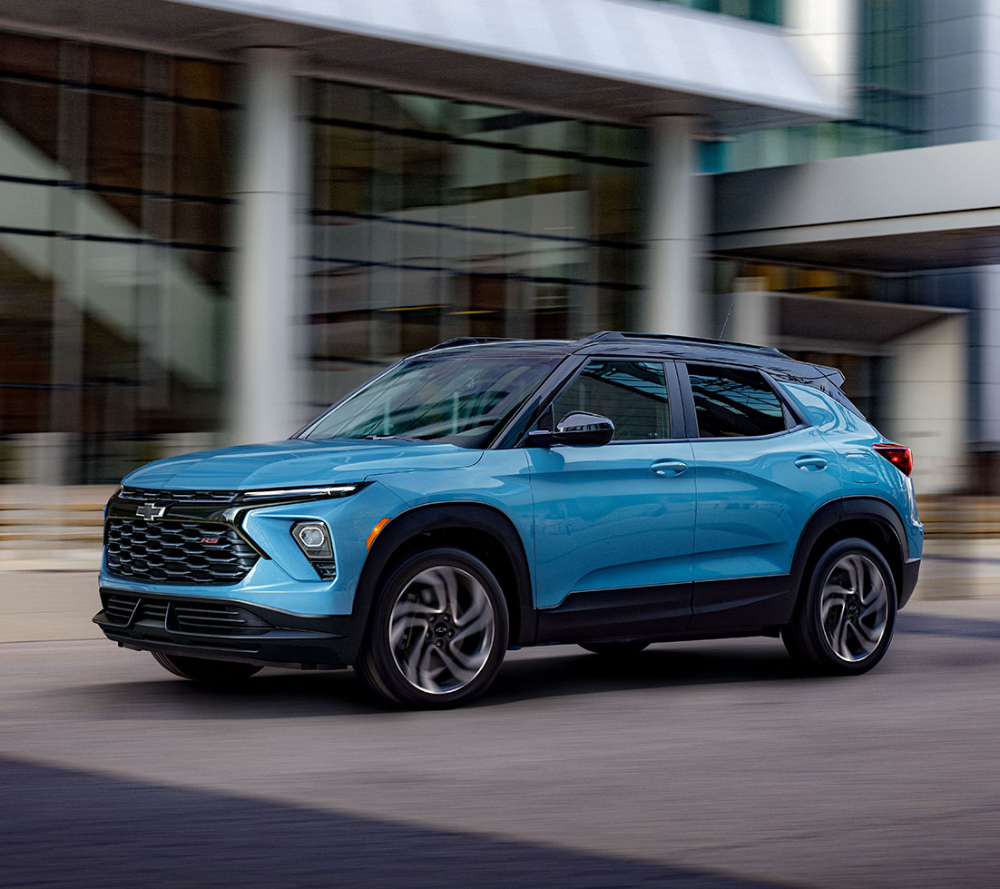 A light blue Chevrolet Trailblazer cruises through a modern urban setting