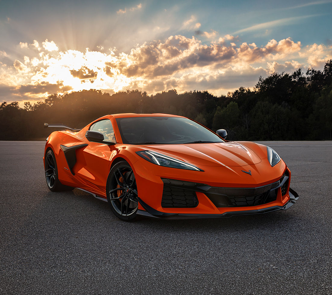 Chevrolet Corvette d'un orange éclatant sur un parking en asphalte, à l'heure dorée