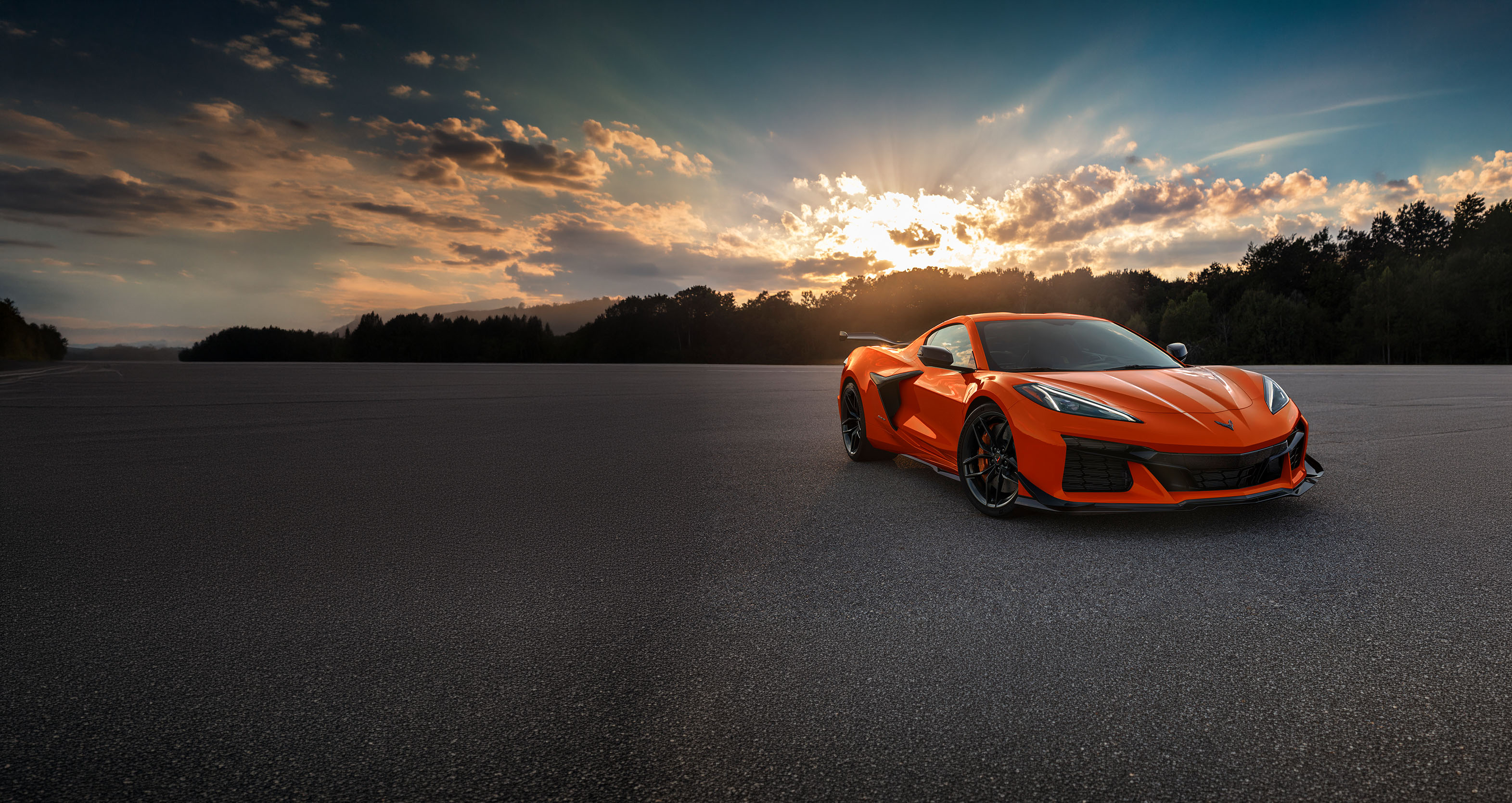 Chevrolet Corvette d'un orange éclatant sur un parking en asphalte, à l'heure dorée