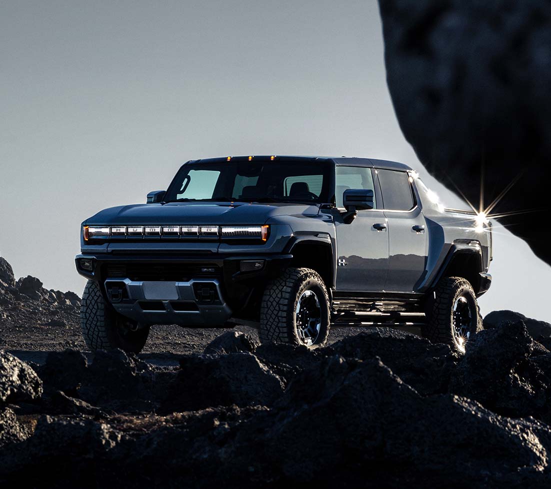 Blue GMC HUMMER EV SUT on a mountain road