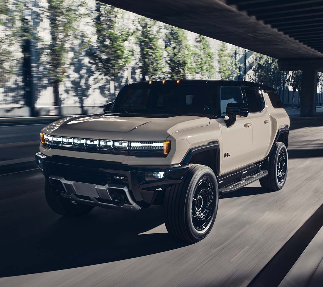 Blue GMC HUMMER EV SUV driving on a mountain road