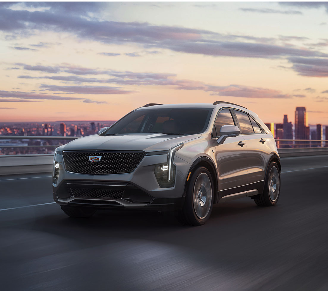 Cadillac XT4 is driving down a city street at sunset