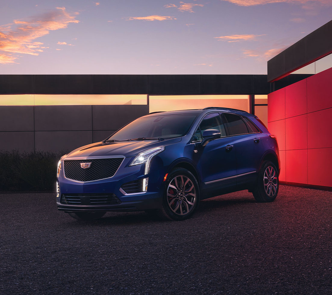 Blue Cadillac XT5 is parked in front of a building