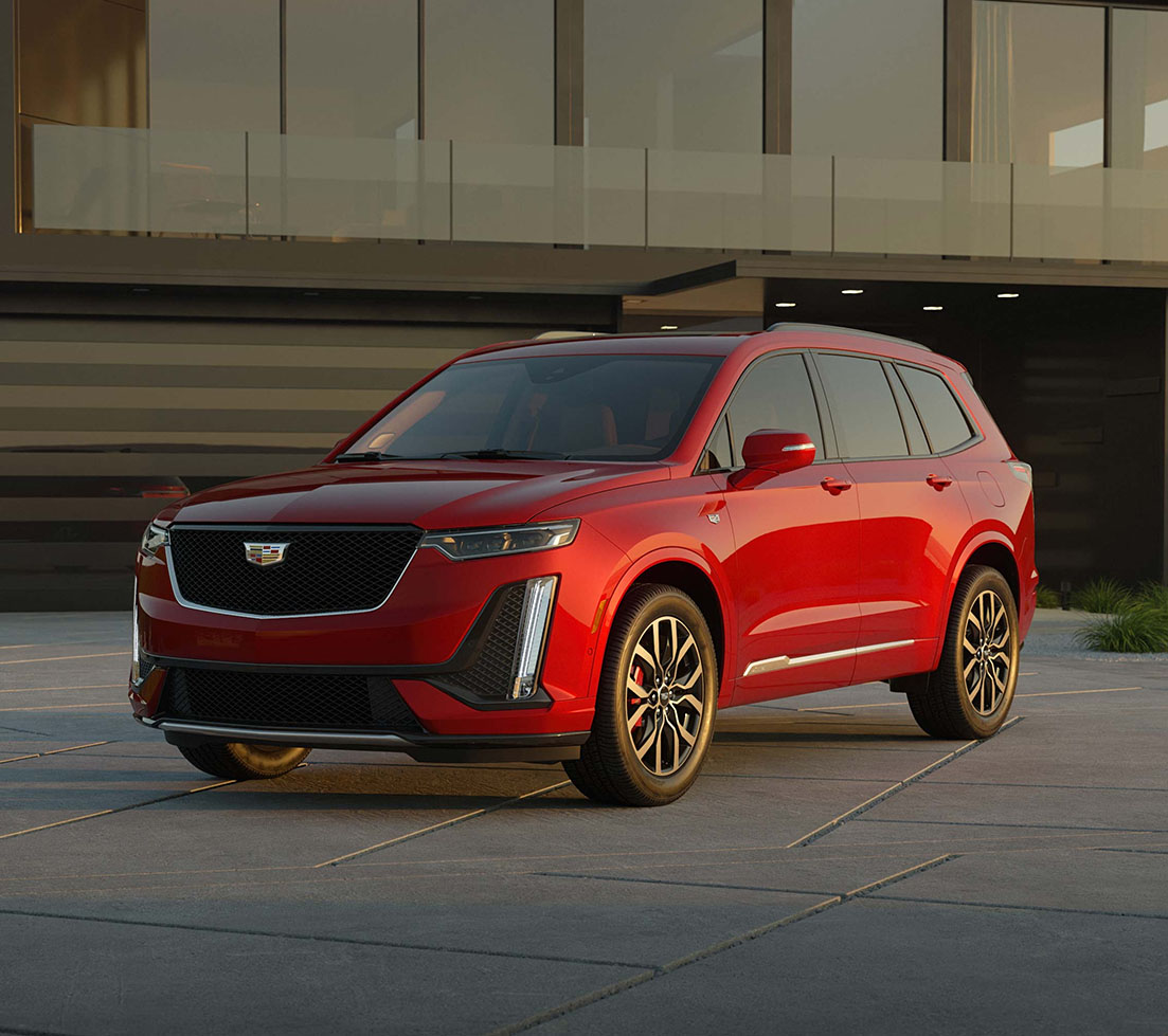 Red Cadillac XT6 is parked in front of a house