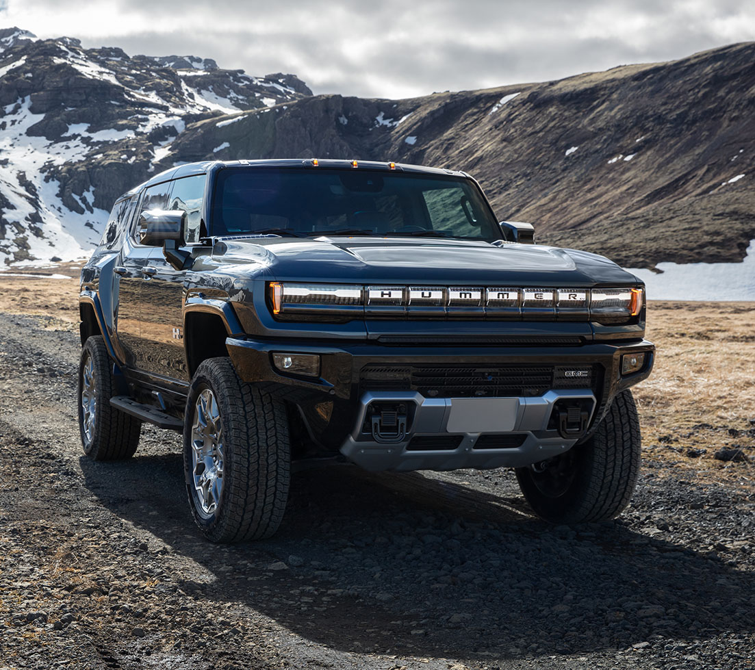 Blue GMC HUMMER EV SUV driving on a mountain road